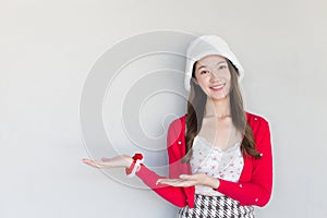 Beautiful Asian woman who wears red coat and white hat as a Santy girl acts her hand to present something on the white background