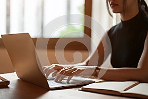 A beautiful Asian woman working on her laptop, typing on the keyboard, responding to emails