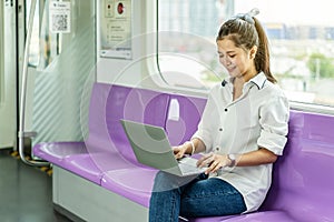 Beautiful asian woman working urgently on a laptop computer at the .electric train in the morning photo