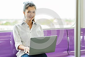 Beautiful asian woman working urgently on a laptop computer at the .electric train in the morning