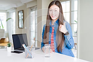 Beautiful Asian woman working using computer laptop doing happy thumbs up gesture with hand