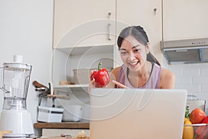 Beautiful Asian woman in workout clothes searches for healthy recipes online on her laptop. while preparing healthy food