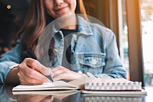 A beautiful asian woman writing on a blank notebook on the table