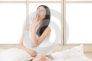 Beautiful asian woman yawn and holding pillow in morning