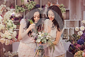 Beautiful asian women florists happy working in flower store with a lot of spring flowers