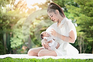 Beautiful Asian young mother  or single mom with new born baby girl are feeding milk from bottle in the park. concept of duties of