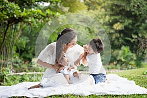 Beautiful Asian young mother  or single mom with new born baby girl and son are doing activities and relaxing in the park. concept