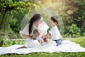 Beautiful Asian young mother  or single mom with new born baby girl and son are doing activities and relaxing in the park. concept