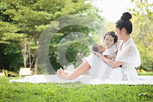 Beautiful Asian young mother  or single mom with new born baby girl and son are doing activities and relaxing in the park. concept