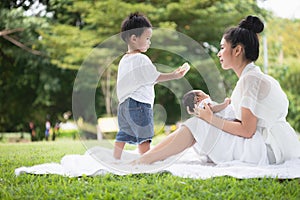 Beautiful Asian young mother  or single mom with new born baby girl and son are doing activities and relaxing in the park. concept