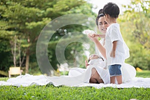 Beautiful Asian young mother  or single mom with new born baby girl and son are doing activities and relaxing in the park. concept
