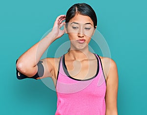 Beautiful asian young sport woman wearing sportswear and arm band confuse and wonder about question