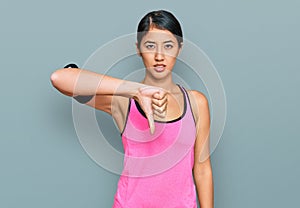 Beautiful asian young sport woman wearing sportswear and arm band looking unhappy and angry showing rejection and negative with