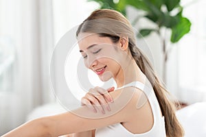 Beautiful Asian young woman apply cream or lotion on her arm for protect dry skin for moisturizing on skin. Healthy skin of young