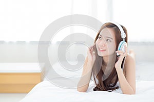 Beautiful asian young woman enjoy listen music with headphone while lying in bedroom