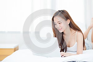 Beautiful asian young woman lying on bed using laptop at bedroom for leisure and relax