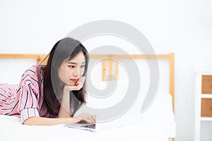 Beautiful asian young woman lying on bed using laptop at bedroom for leisure and relax, freelance with girl working notebook,