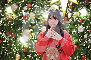 Beautiful Asian young woman with a red sweater with Christmas tree light