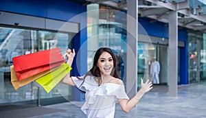 Beautiful asian young woman with shopping bags with smile while standing at the clothing store. Happiness, consumerism, sale and