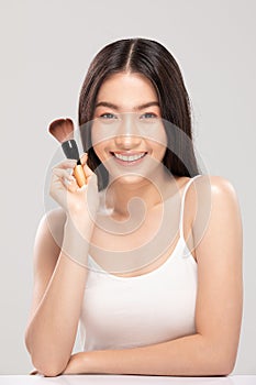 Beautiful Asian young woman smile and holding make up brush