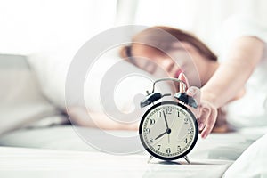 Beautiful asian young woman turn off alarm clock in morning, wake up for sleep with alarm clock