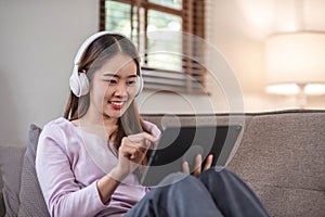 beautiful asian young woman wear casual sit on couch using computer laptop entertain with social media relax smile and