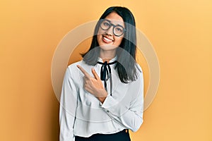 Beautiful asian young woman wearing business shirt smiling cheerful pointing with hand and finger up to the side