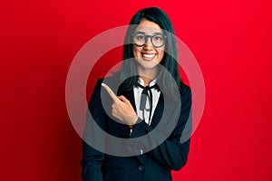 Beautiful asian young woman wearing business suit with a big smile on face, pointing with hand and finger to the side looking at