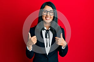 Beautiful asian young woman wearing business suit success sign doing positive gesture with hand, thumbs up smiling and happy