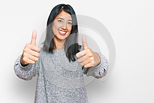 Beautiful asian young woman wearing casual clothes approving doing positive gesture with hand, thumbs up smiling and happy for