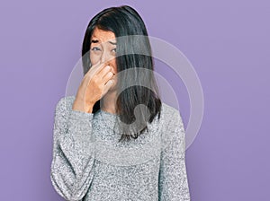 Beautiful asian young woman wearing casual clothes smelling something stinky and disgusting, intolerable smell, holding breath