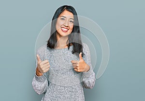 Beautiful asian young woman wearing casual clothes success sign doing positive gesture with hand, thumbs up smiling and happy