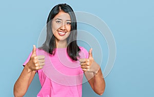 Beautiful asian young woman wearing casual pink t shirt approving doing positive gesture with hand, thumbs up smiling and happy