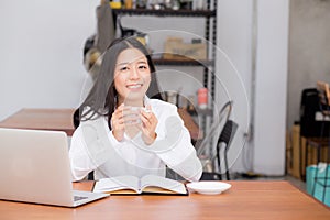 Beautiful asian young woman working online on laptop and drink coffee sitting at coffee shop.