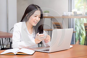 Beautiful asian young woman working online on laptop sitting at coffee shop