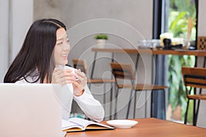 Beautiful asian young woman working online on laptop sitting at coffee shop