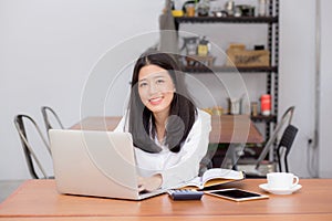 Beautiful asian young woman working online on laptop sitting at coffee shop.