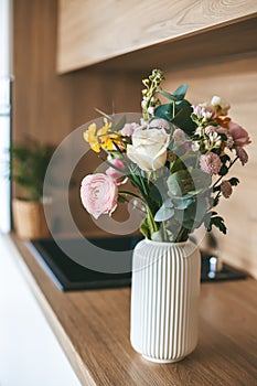 A beautiful assortment of flowers in a white vase, placed on the countertop of a modern kitchen