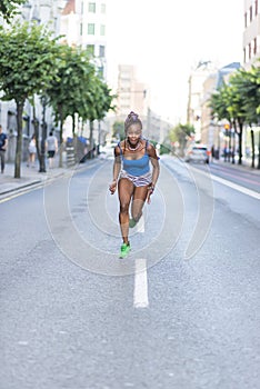 Beautiful athlete african woman running in the street, health lifestyle c