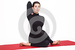 Beautiful athletic girl in black suit doing yoga. gomukhasana asana - pose cow's head. Isolated on white background.