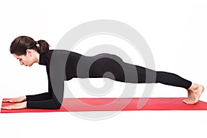 Beautiful athletic girl in black suit doing yoga. Kumbhasana asana plank pose on elbows. Isolated white background. photo