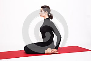Beautiful athletic girl in a black suit doing yoga. Virasana asana hero pose. Isolated on white background.