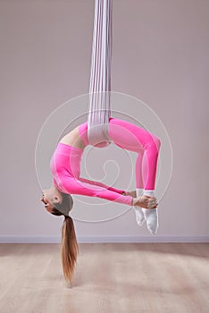 Beautiful athletic girl in a pink uniform does an anti-gravity yoga and airstretching pose. The concept of a healthy lifestyle