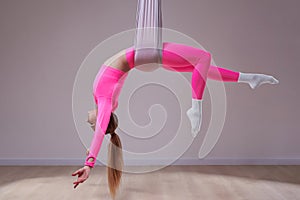 Beautiful athletic girl in a pink uniform does an anti-gravity yoga and airstretching pose. The concept of a healthy lifestyle