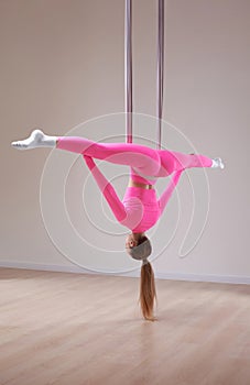 Beautiful athletic girl in a pink uniform does an anti-gravity yoga and airstretching pose. The concept of a healthy lifestyle