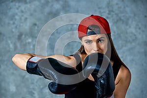Beautiful athletic girl posing in pink boxing gloves on a gray background. Copy space. Concept sport, fight, goal