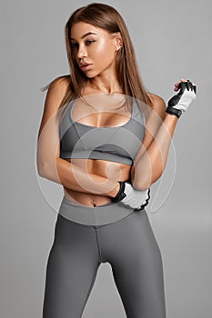 Beautiful athletic girl, sexy fitness woman on the gray background