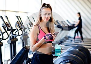 Beautiful athletic girl in the sportswear uses the fitness app on your smartphones in the gym. Athlete enjoys her training.