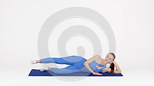 Beautiful Athletic Lady Training In Studio, Doing Side Leg Lift Exercise