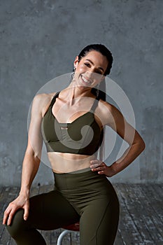 Beautiful athletic latino girl posing for the camera. Portrait of a fitness girl on a gray background in khaki overalls